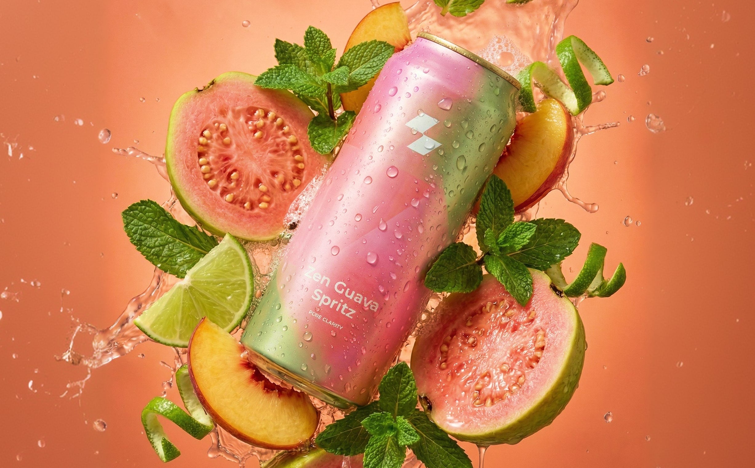 Pink can with guava spritz surrounded by guava slices, lime, and mint leaves on a peach-colored background.