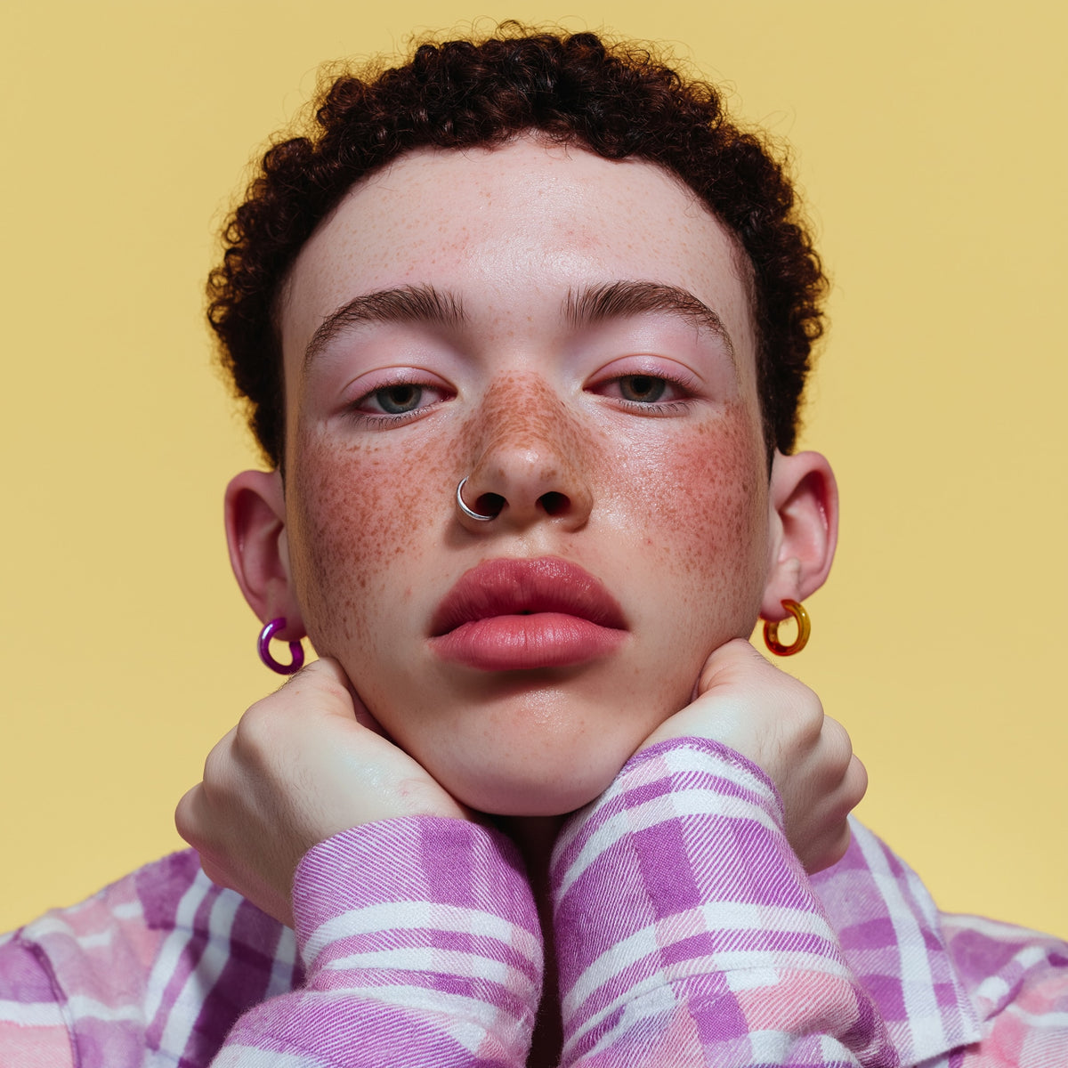 Person wearing a pink and white checkered shirt with a yellow background
