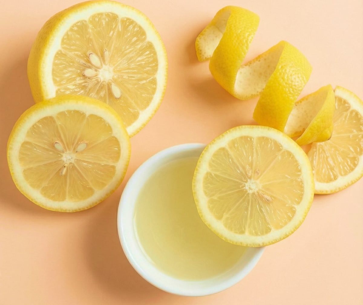 Lemon slices and a bowl of lemon juice on a peach background