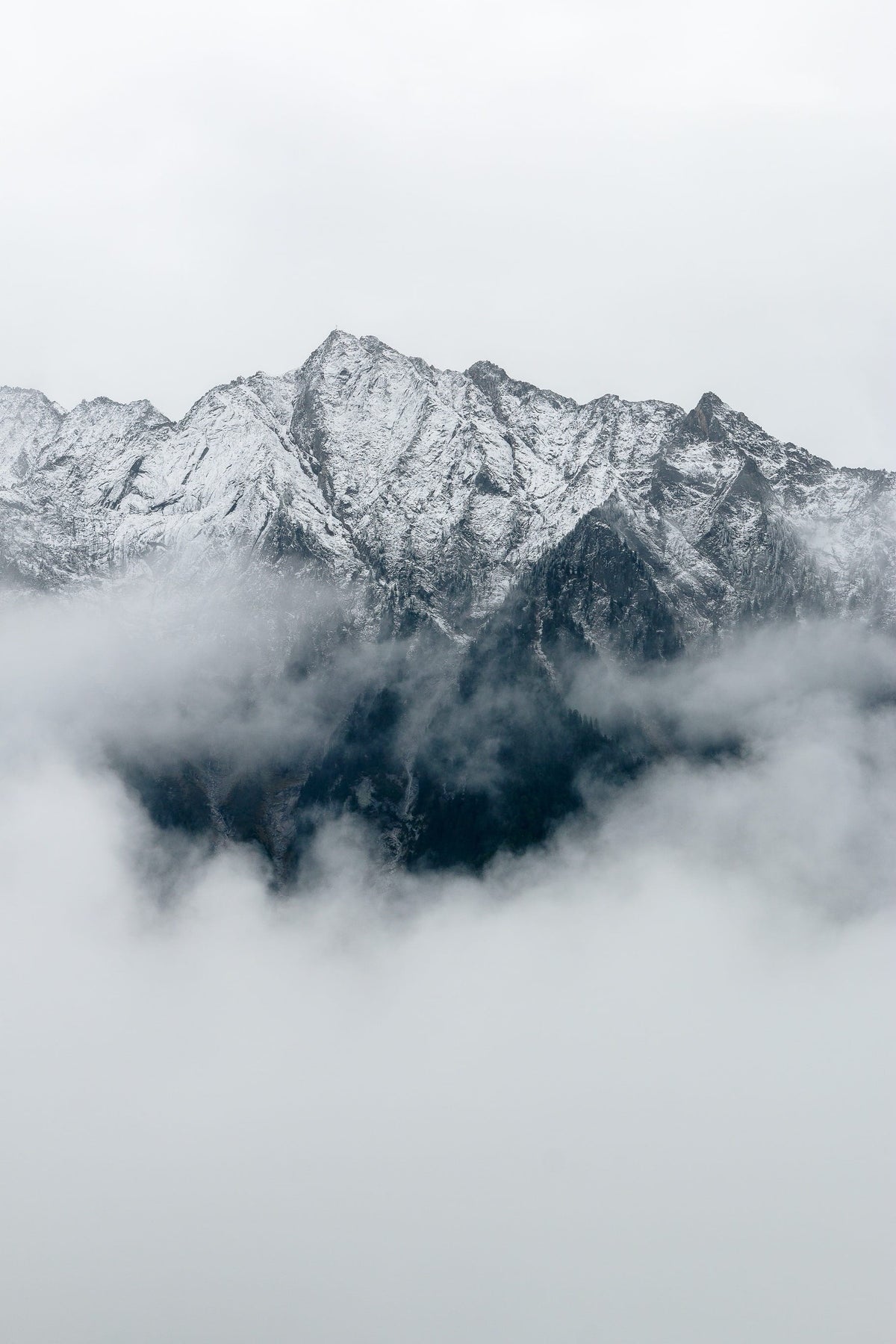 Snow-capped mountains partially obscured by clouds