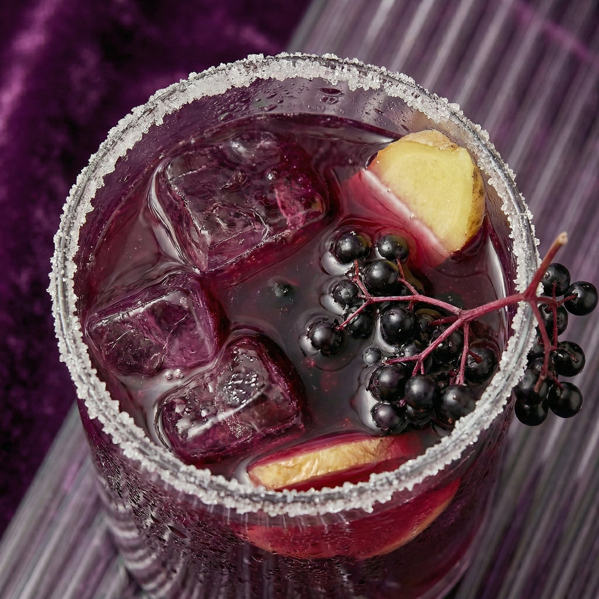 Purple cocktail with ice, fruit, and berries in a glass with a purple background