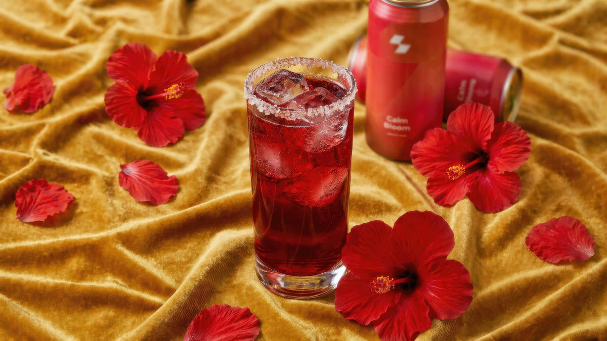 Red floral cocktail with hibiscus flowers and sparkling drink cans